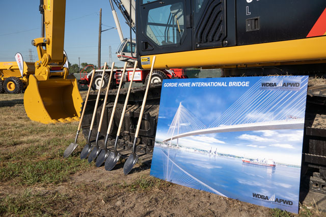 Construction equipment with a printed rendering of the Gordie Howe International Bridge in front of it.